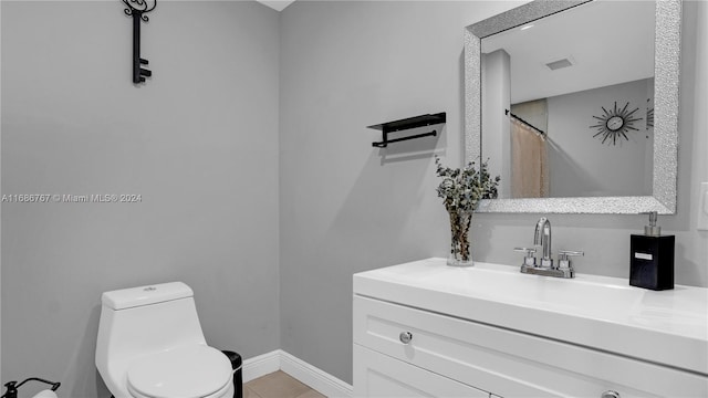 bathroom with toilet, vanity, and tile patterned flooring