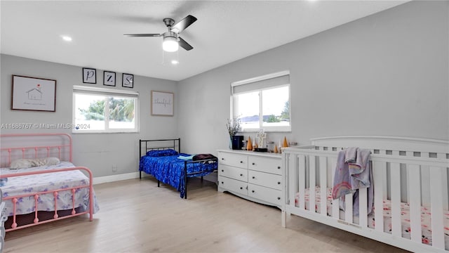 bedroom featuring light hardwood / wood-style floors, multiple windows, and ceiling fan