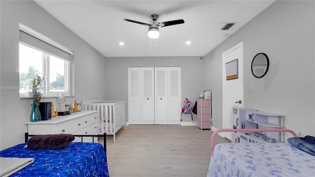 bedroom with light hardwood / wood-style flooring, ceiling fan, and a closet