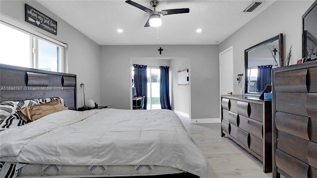 bedroom with ceiling fan, multiple windows, light hardwood / wood-style flooring, and a textured ceiling