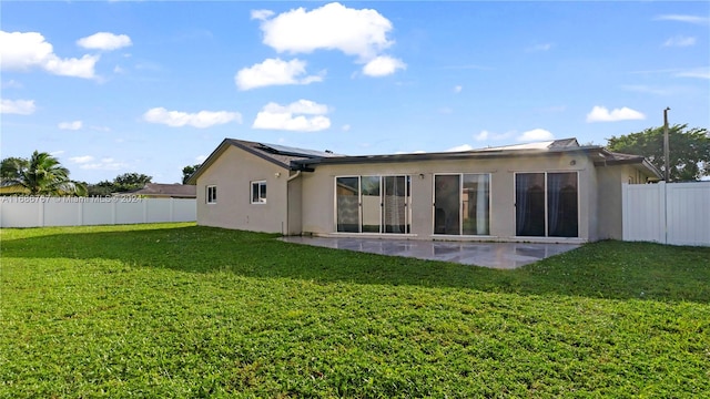 back of house with a lawn, solar panels, and a patio area