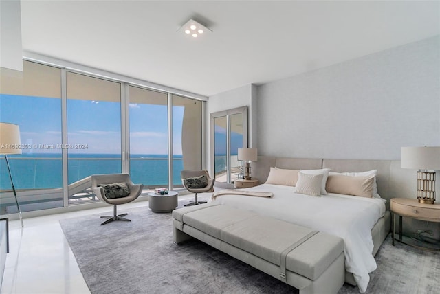 bedroom featuring expansive windows, a water view, and access to exterior