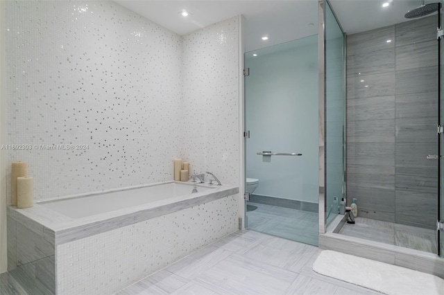 bathroom featuring toilet, separate shower and tub, and tile walls