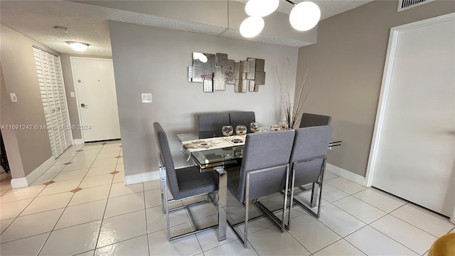 tiled dining room with a textured ceiling and a notable chandelier