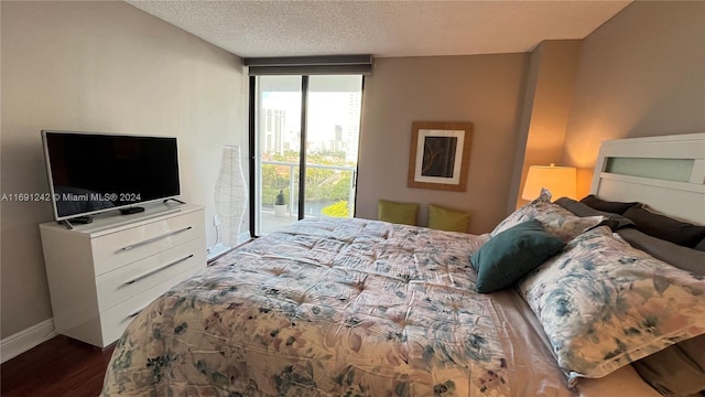 bedroom with wood-type flooring, a textured ceiling, access to outside, and expansive windows