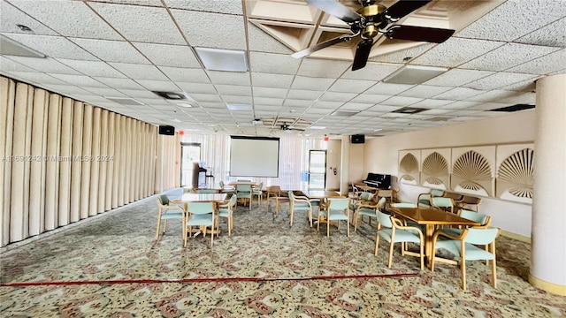 dining area with ceiling fan, a drop ceiling, and carpet floors