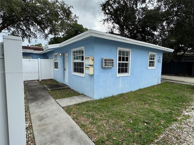 view of home's exterior with a wall unit AC and a yard