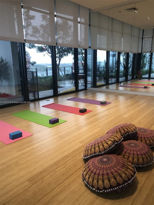 exercise room with a towering ceiling, hardwood / wood-style floors, and a wall of windows