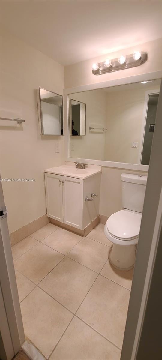 bathroom with toilet, vanity, and tile patterned flooring