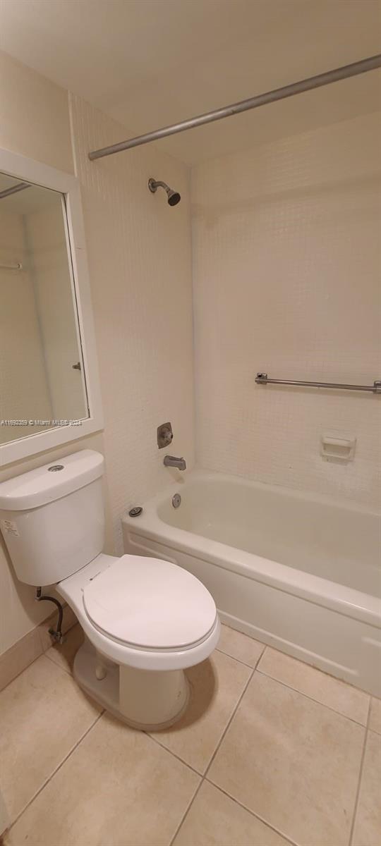 bathroom with toilet, tiled shower / bath, and tile patterned floors