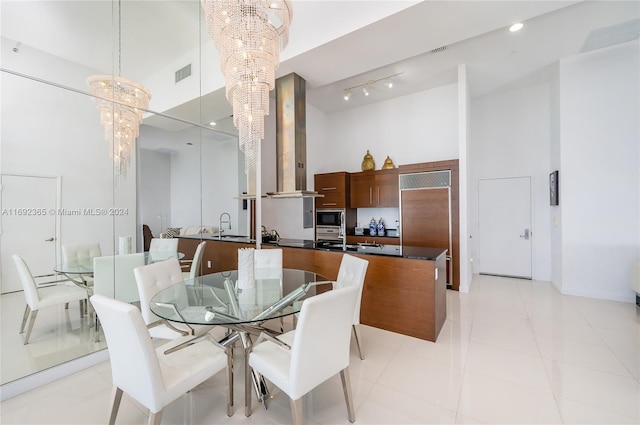 dining room with a high ceiling, sink, light tile patterned floors, and a notable chandelier