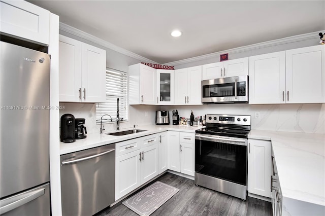 kitchen featuring light stone countertops, white cabinetry, stainless steel appliances, and ornamental molding