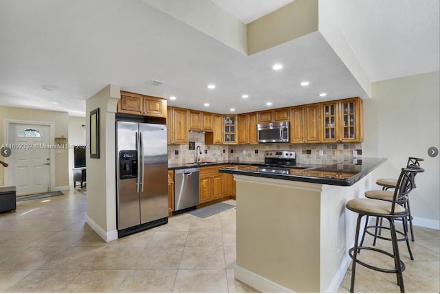 kitchen with kitchen peninsula, a breakfast bar area, tasteful backsplash, sink, and appliances with stainless steel finishes