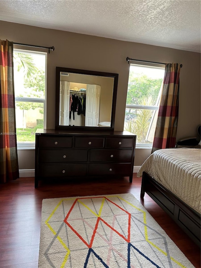 bedroom featuring hardwood / wood-style floors, a textured ceiling, a closet, and a spacious closet