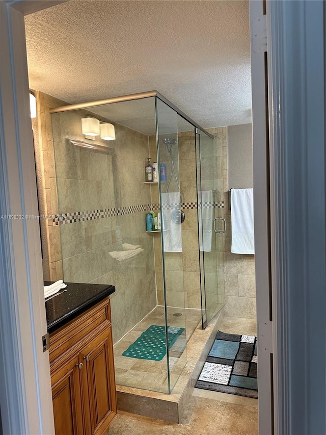 bathroom with vanity, a shower with door, and a textured ceiling