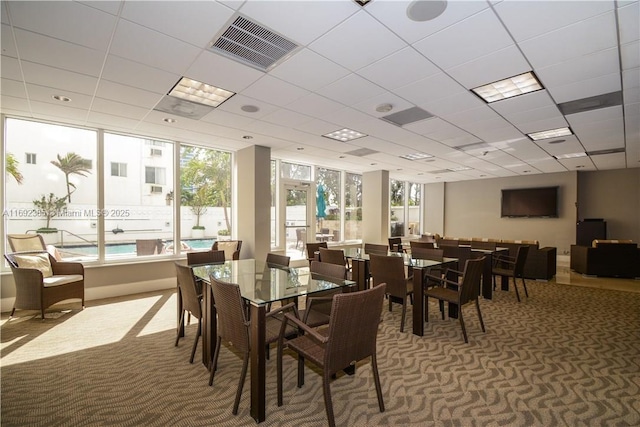 carpeted dining room featuring a drop ceiling