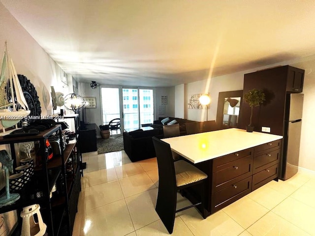 kitchen with stainless steel refrigerator, dark brown cabinetry, a breakfast bar area, and light tile patterned floors