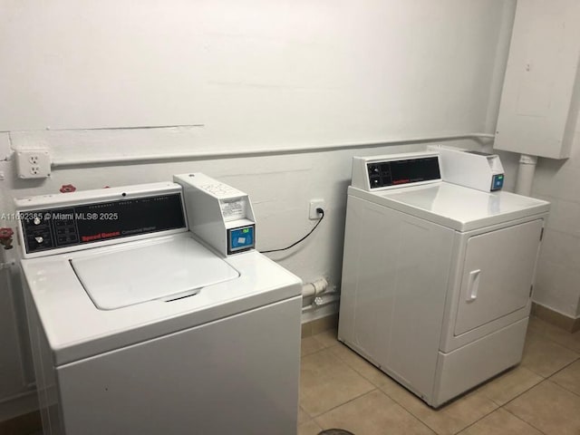 laundry area with electric panel, independent washer and dryer, and light tile patterned flooring