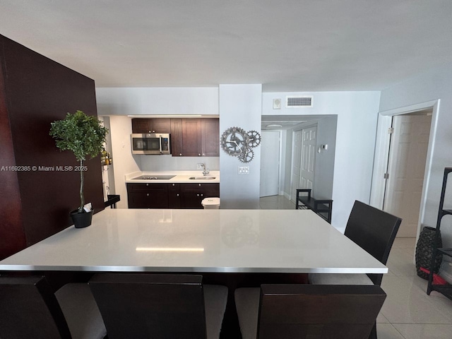 kitchen with black electric cooktop, light tile patterned floors, sink, and a center island