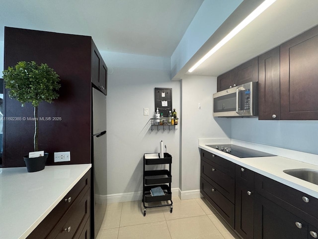 kitchen featuring stainless steel appliances, sink, dark brown cabinets, and light tile patterned floors