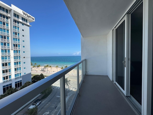 balcony with a water view and a view of the beach