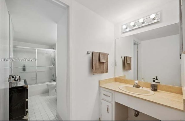 full bathroom featuring toilet, vanity, bath / shower combo with glass door, and tile patterned floors