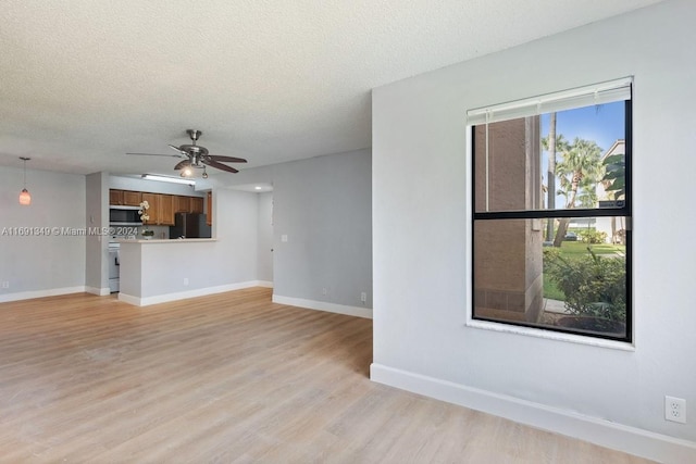 unfurnished living room with ceiling fan, a textured ceiling, and light hardwood / wood-style floors