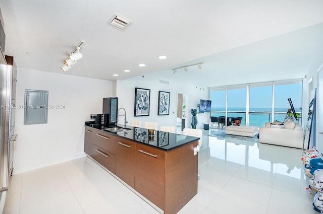 kitchen featuring cooktop, sink, a wall of windows, rail lighting, and light tile patterned floors