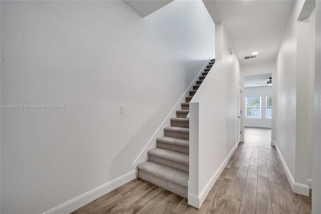 stairs featuring hardwood / wood-style floors and ceiling fan