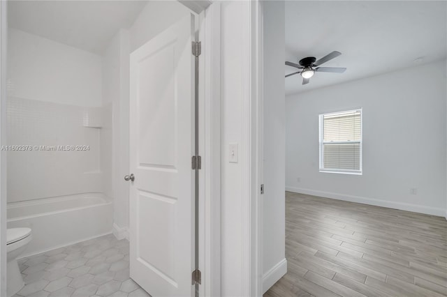 bathroom featuring toilet, shower / bathing tub combination, hardwood / wood-style flooring, and ceiling fan