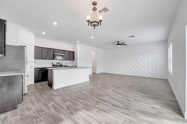 kitchen featuring sink, appliances with stainless steel finishes, ceiling fan with notable chandelier, an island with sink, and pendant lighting