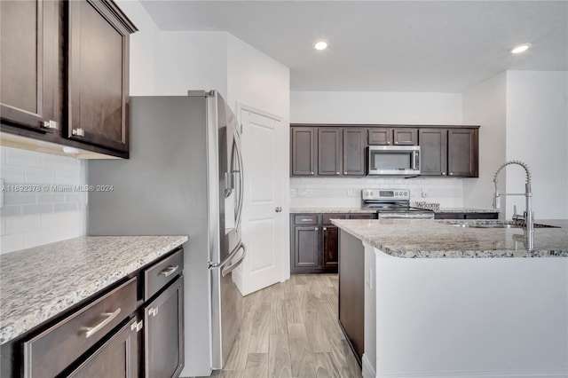 kitchen featuring tasteful backsplash, stainless steel appliances, dark brown cabinetry, sink, and light hardwood / wood-style floors