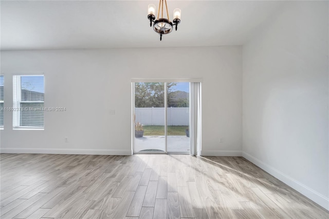 unfurnished room with light hardwood / wood-style floors and a chandelier