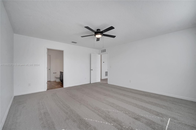 unfurnished bedroom with ceiling fan, ensuite bath, a textured ceiling, and carpet floors