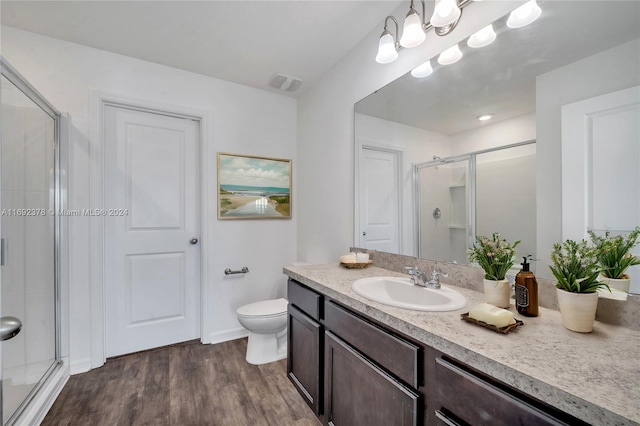 bathroom featuring toilet, vanity, an enclosed shower, and hardwood / wood-style flooring