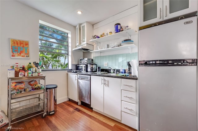 kitchen featuring white cabinets, decorative backsplash, hardwood / wood-style flooring, sink, and appliances with stainless steel finishes