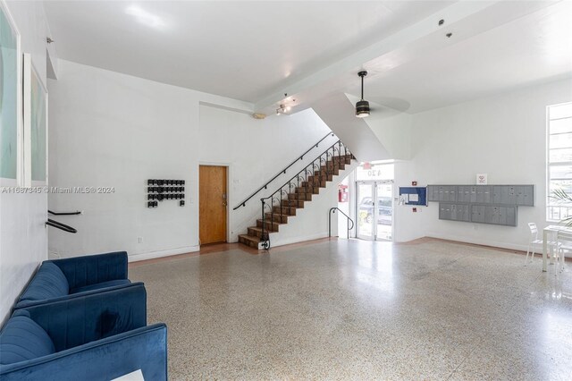 420 15th St Unit 107, Miami Beach, FL 33139 - unfurnished living room featuring speckled floor, mail area, stairs, a ceiling fan, and baseboards