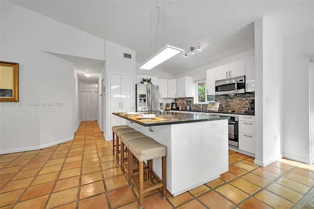 kitchen with a breakfast bar, a center island, lofted ceiling, white cabinetry, and stainless steel appliances