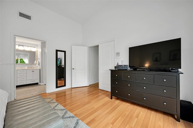 bedroom featuring connected bathroom, high vaulted ceiling, and light hardwood / wood-style floors