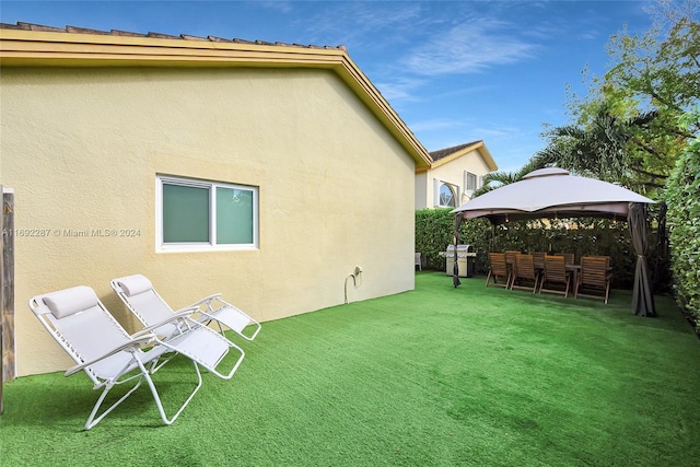 rear view of house with a gazebo and a yard