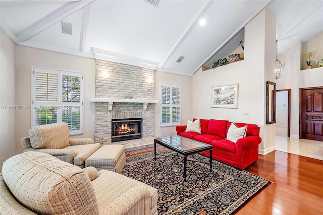 living room featuring a textured ceiling, high vaulted ceiling, beamed ceiling, a fireplace, and hardwood / wood-style floors