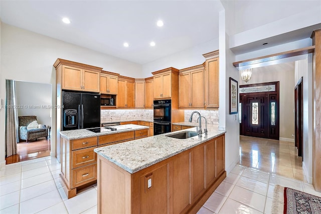 kitchen with sink, light stone counters, kitchen peninsula, light tile patterned floors, and black appliances