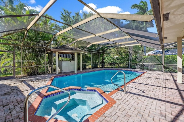 view of swimming pool with glass enclosure, an in ground hot tub, and a patio