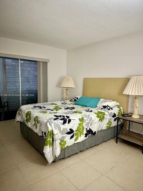 bedroom with access to outside, a textured ceiling, and light tile patterned floors