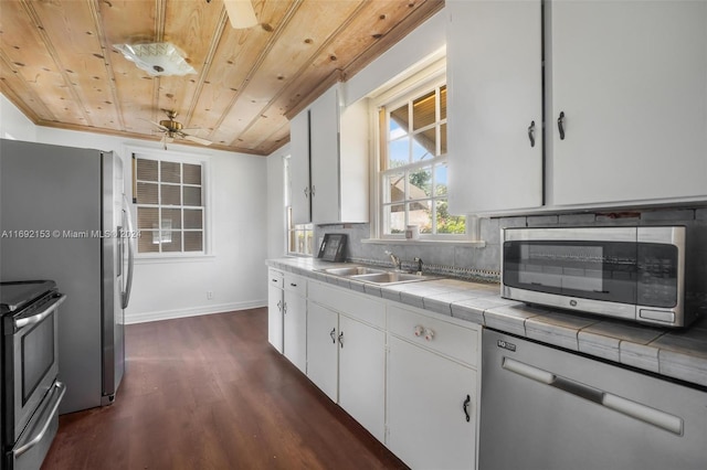 kitchen with tile counters, stainless steel appliances, dark hardwood / wood-style flooring, wood ceiling, and white cabinets