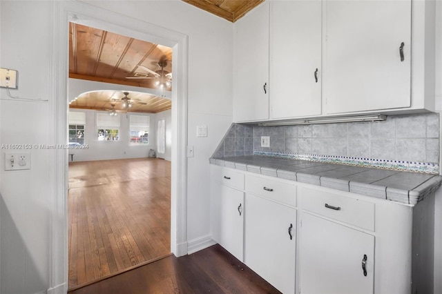 kitchen with backsplash, dark hardwood / wood-style flooring, white cabinets, tile countertops, and wooden ceiling