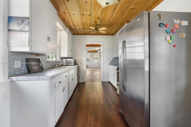 kitchen featuring stainless steel appliances, white cabinetry, backsplash, dark wood-type flooring, and ceiling fan