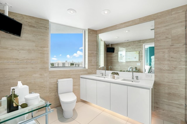 full bathroom with tile walls, a sink, toilet, and tile patterned floors