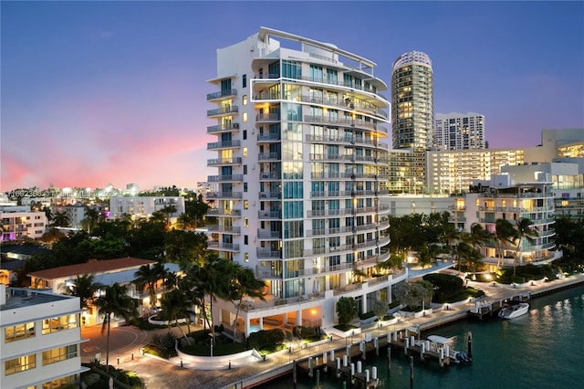 property at dusk with a water view and a city view