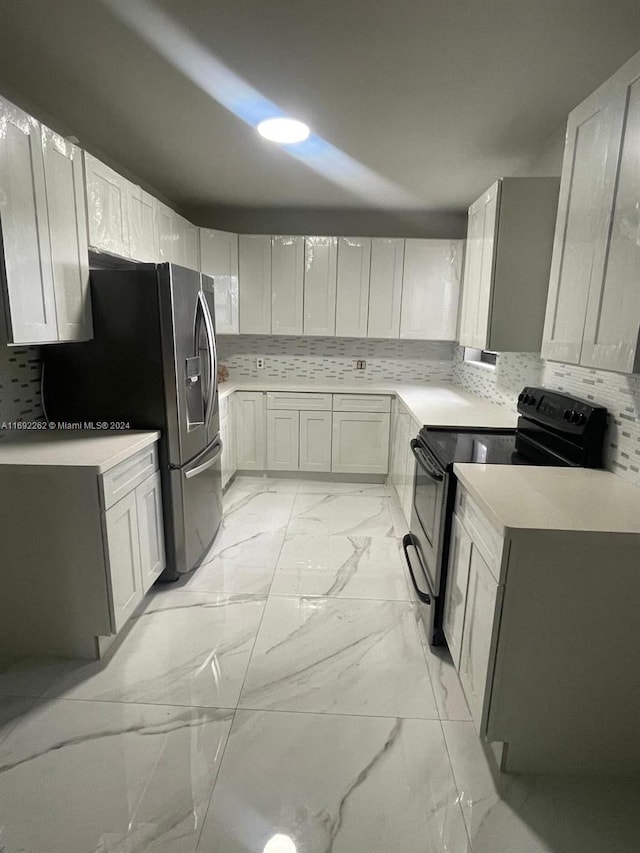 kitchen featuring white cabinets, stainless steel fridge, black range with electric stovetop, and tasteful backsplash